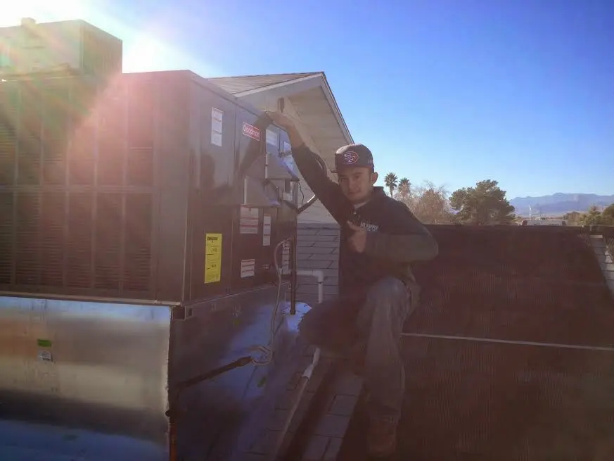 HVAC technician performing AC Tune-Up on a rooftop unit in Hays